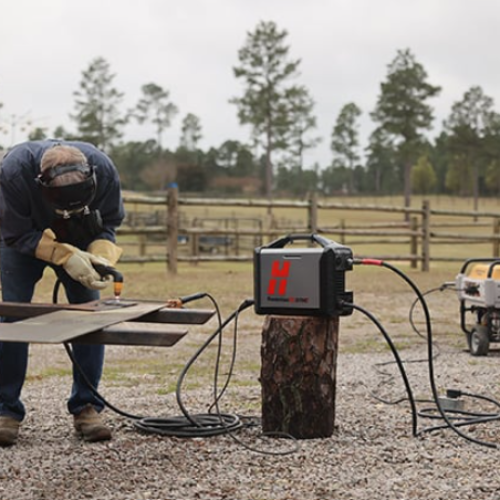 A person wearing protective gear cuts metal sheet with a Hypertherm sync 45 plasma cutter